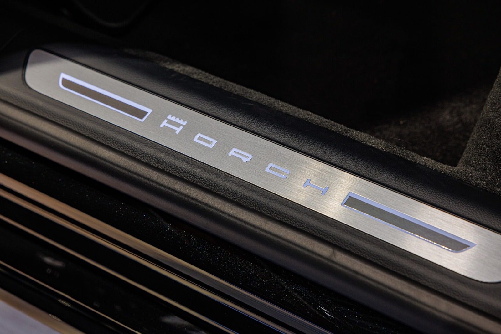 Brushed chrome door sill trim on a luxury car, cleaned and free of dust against dark carpet
