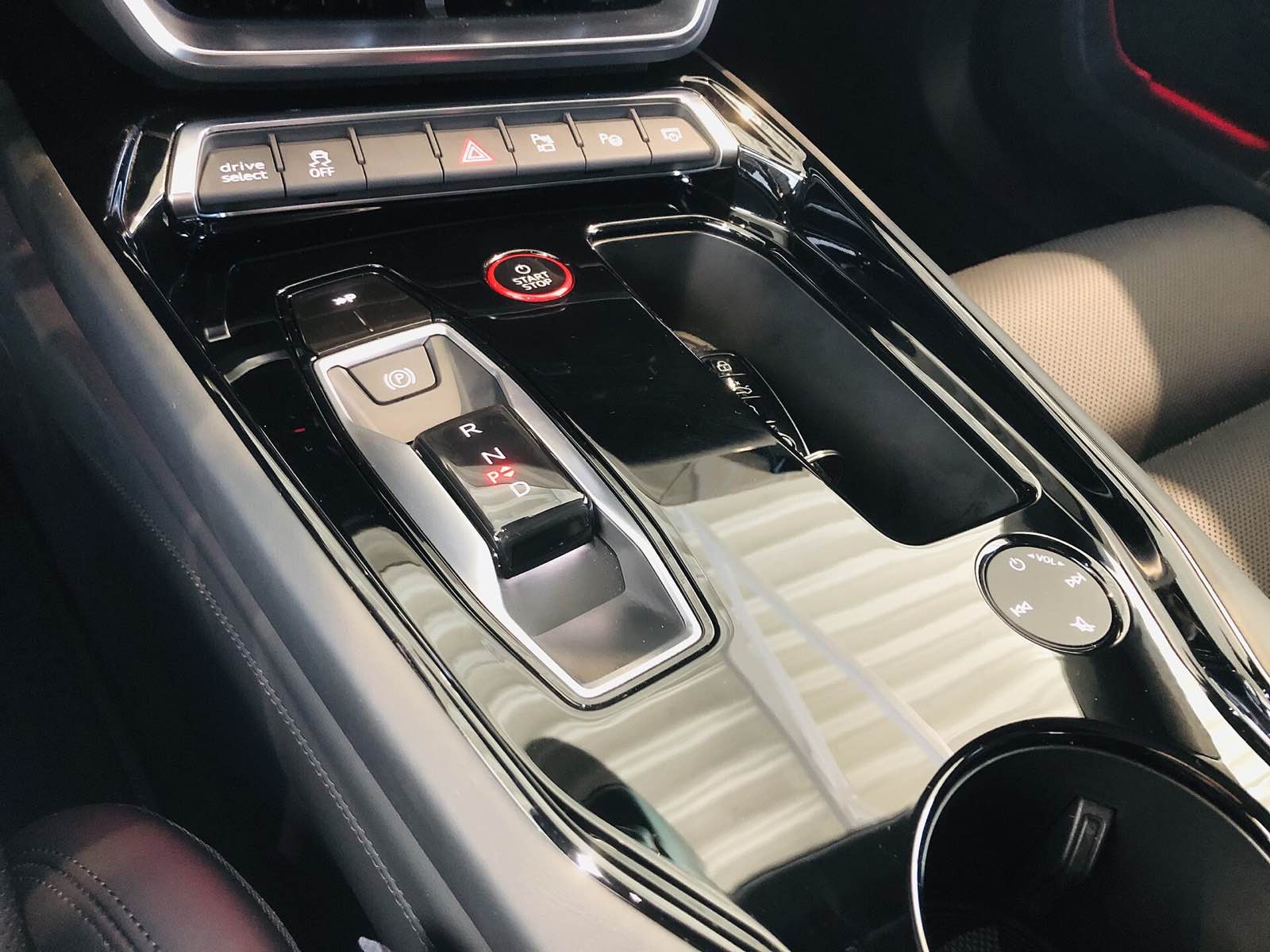 Detailed center console of a modern car with clean piano-black trim and polished chrome switchgear
